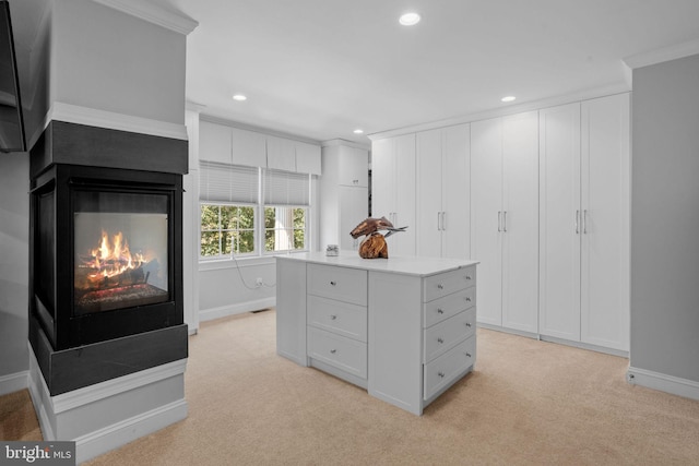 walk in closet with a multi sided fireplace and light carpet