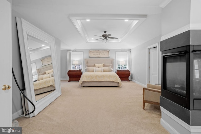 carpeted bedroom with a raised ceiling, ceiling fan, and crown molding