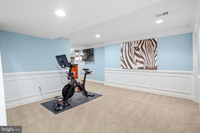 exercise area featuring crown molding and light carpet