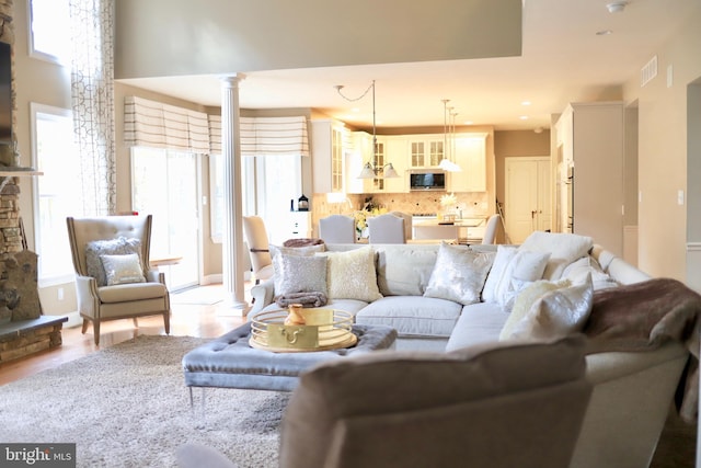 living room with ornate columns, plenty of natural light, and light hardwood / wood-style flooring