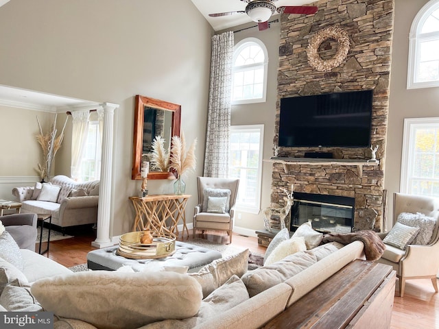 living room featuring ceiling fan, light hardwood / wood-style floors, a stone fireplace, and high vaulted ceiling