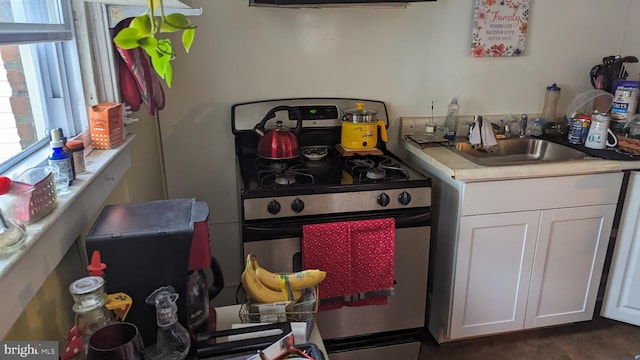 kitchen featuring range, white cabinetry, exhaust hood, dark tile flooring, and sink