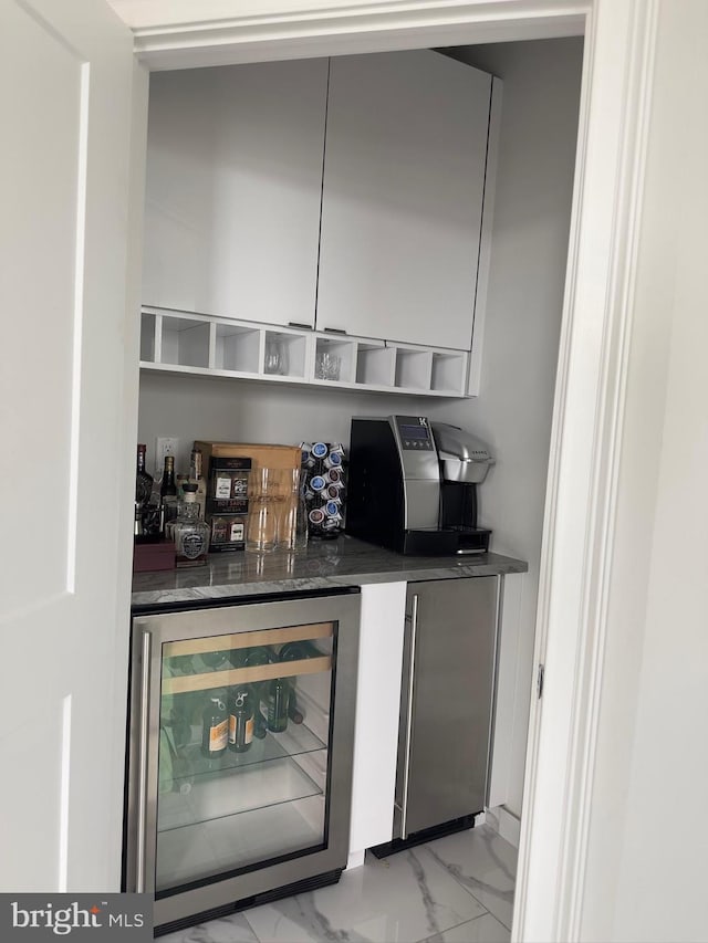 bar with dark stone counters, refrigerator, beverage cooler, and light tile floors