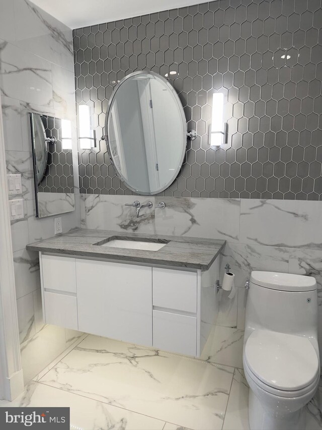 bathroom featuring tile walls, tile flooring, toilet, and vanity