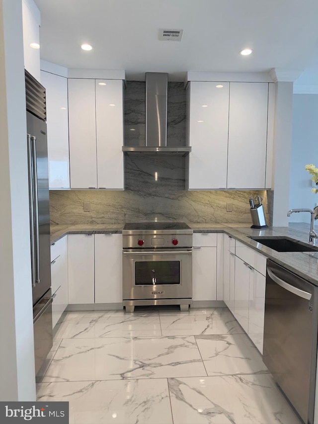 kitchen featuring backsplash, sink, white cabinets, wall chimney exhaust hood, and high quality appliances