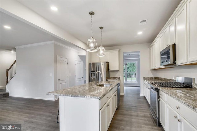 kitchen with white cabinets, a center island with sink, stainless steel appliances, and dark wood-type flooring