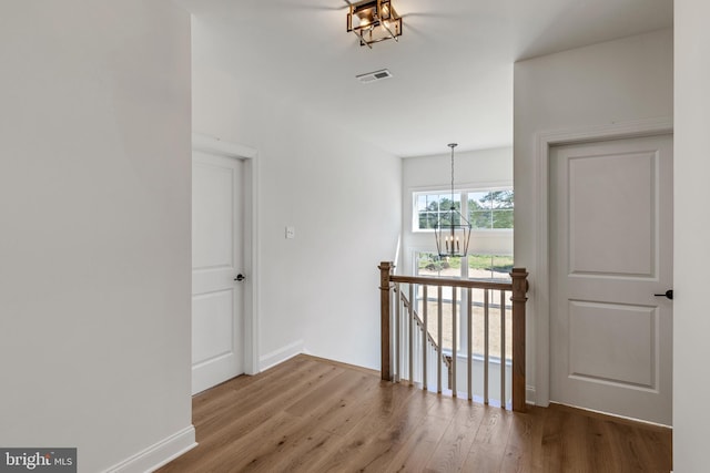 hallway featuring an inviting chandelier and light wood-type flooring