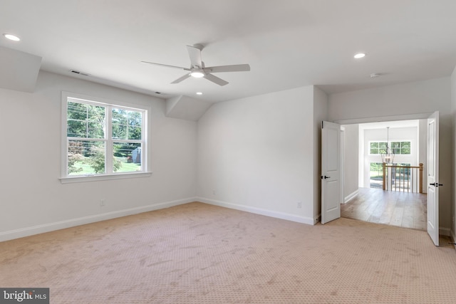 carpeted spare room with ceiling fan with notable chandelier