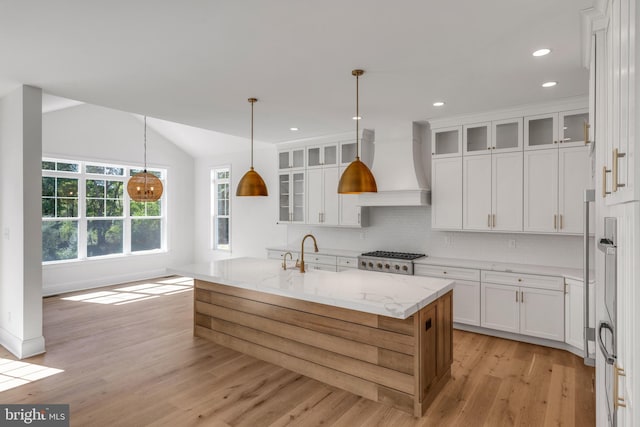 kitchen with custom exhaust hood, range, light hardwood / wood-style floors, and white cabinetry