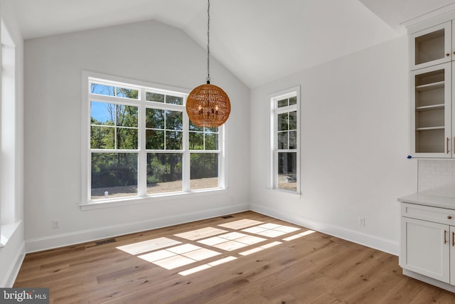 unfurnished dining area featuring lofted ceiling and light hardwood / wood-style floors