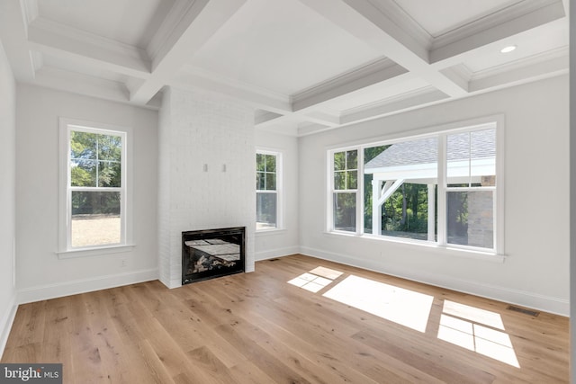 unfurnished living room with plenty of natural light, light hardwood / wood-style flooring, and beamed ceiling