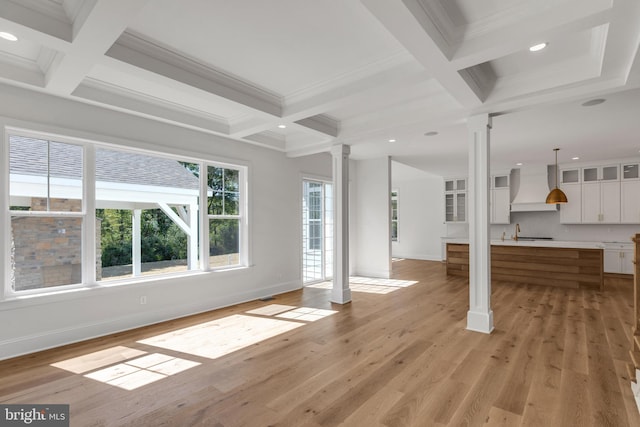 unfurnished living room with coffered ceiling, decorative columns, beamed ceiling, sink, and light hardwood / wood-style flooring