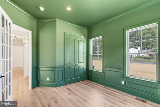 entryway featuring french doors, ornamental molding, a chandelier, and light wood-type flooring