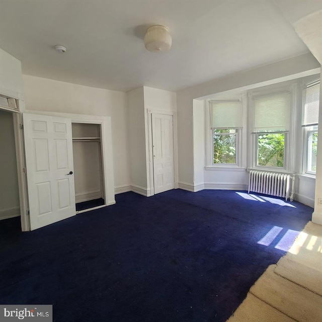 unfurnished bedroom with radiator heating unit and dark colored carpet