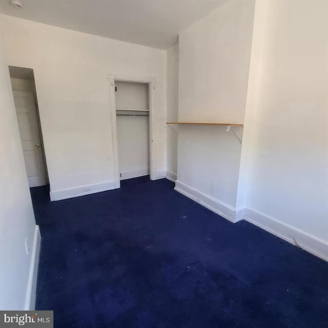 unfurnished bedroom featuring concrete flooring, a closet, and baseboards