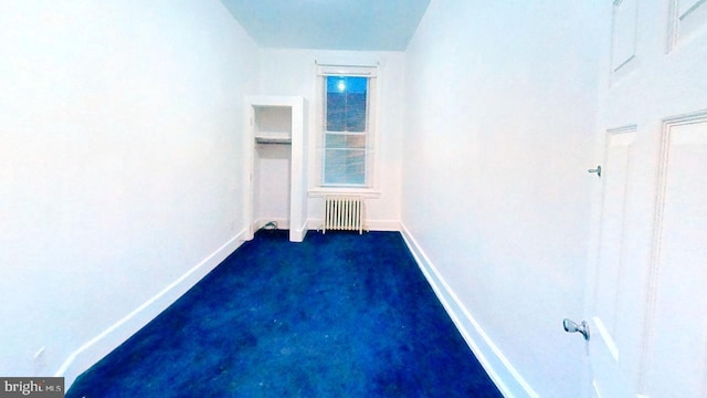 empty room with radiator, baseboards, and dark carpet