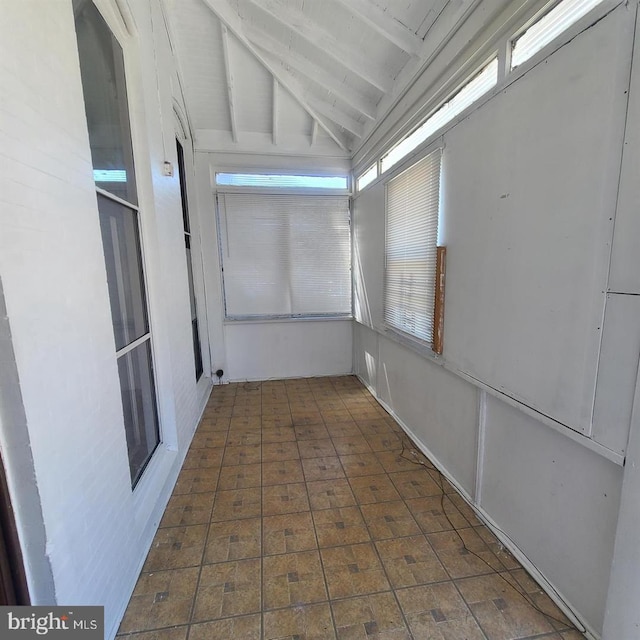 unfurnished sunroom featuring vaulted ceiling with beams