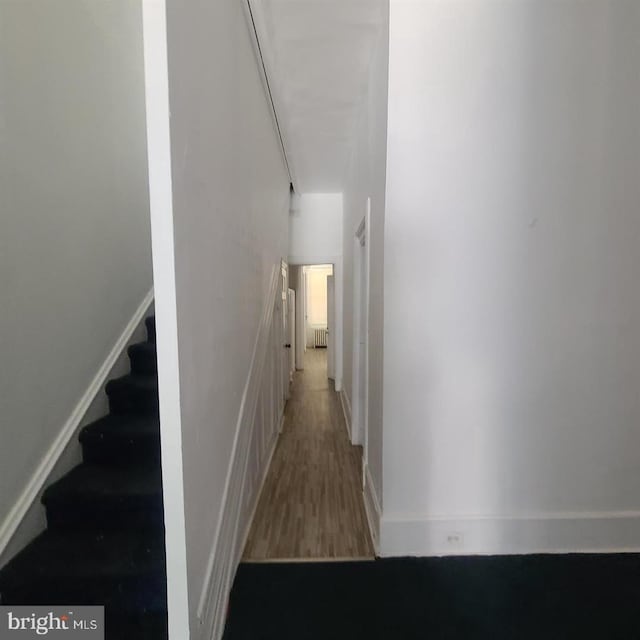 hall with stairway, wood finished floors, and baseboards