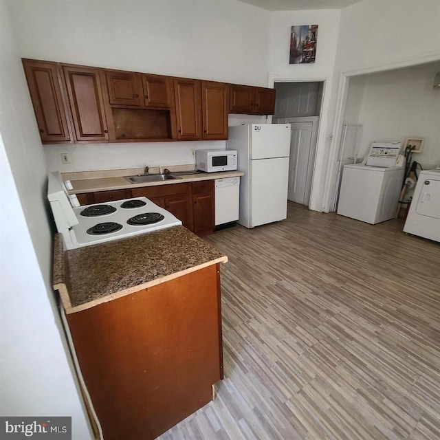 kitchen featuring white appliances, washer / clothes dryer, light wood finished floors, and a sink