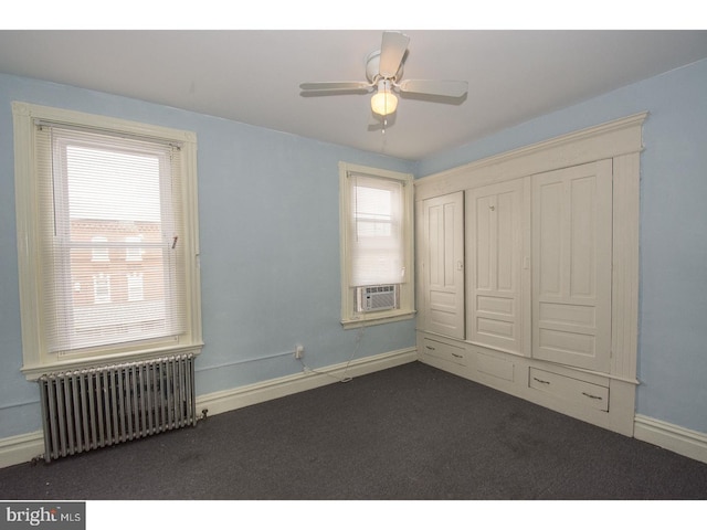 unfurnished bedroom featuring radiator heating unit, ceiling fan, and dark colored carpet