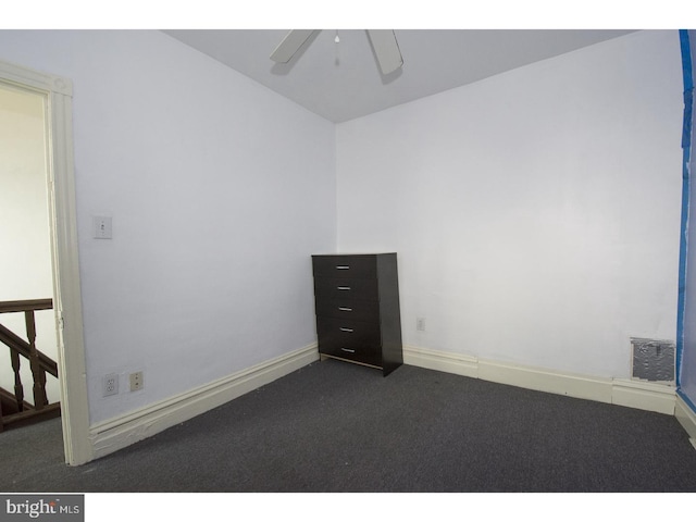 spare room with dark colored carpet and ceiling fan