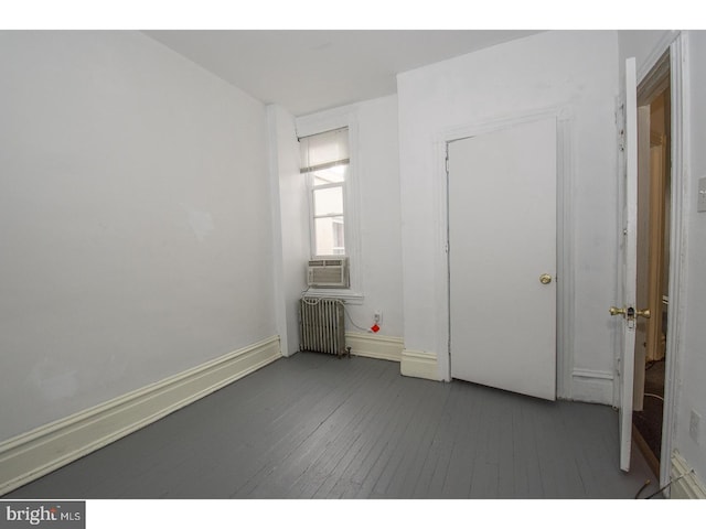 unfurnished bedroom featuring radiator and dark hardwood / wood-style floors