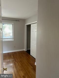 unfurnished bedroom with dark wood-type flooring and a closet