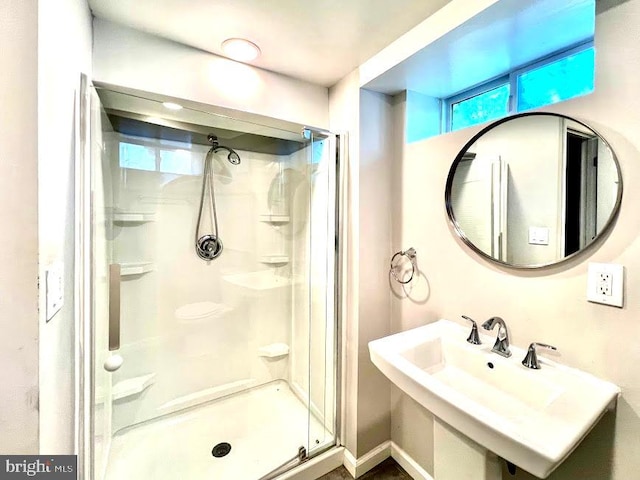 bathroom featuring a shower with shower door and sink