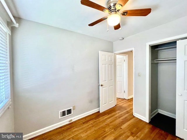 unfurnished bedroom featuring ceiling fan, a closet, and hardwood / wood-style flooring