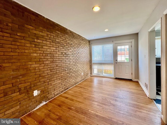 foyer with light hardwood / wood-style floors and brick wall