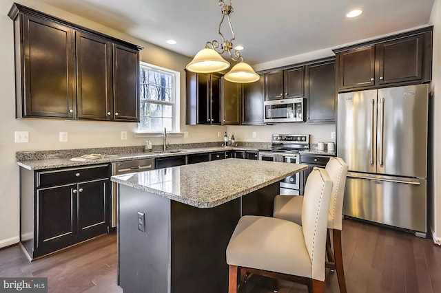 kitchen with pendant lighting, dark wood-type flooring, a center island, and appliances with stainless steel finishes