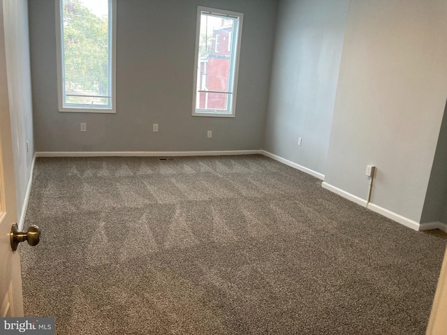 spare room with dark carpet and plenty of natural light