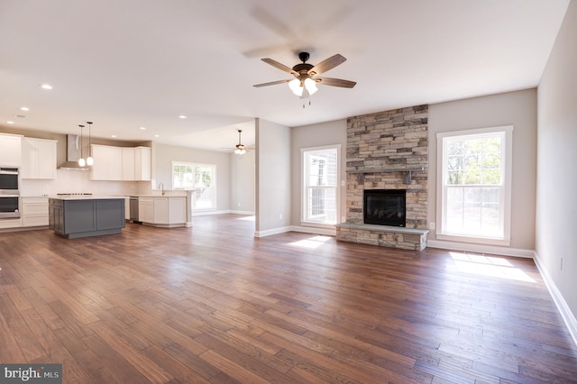 unfurnished living room with ceiling fan, a fireplace, dark hardwood / wood-style floors, and sink