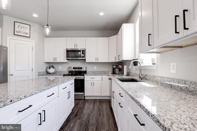 kitchen with appliances with stainless steel finishes, dark hardwood / wood-style flooring, sink, white cabinets, and hanging light fixtures