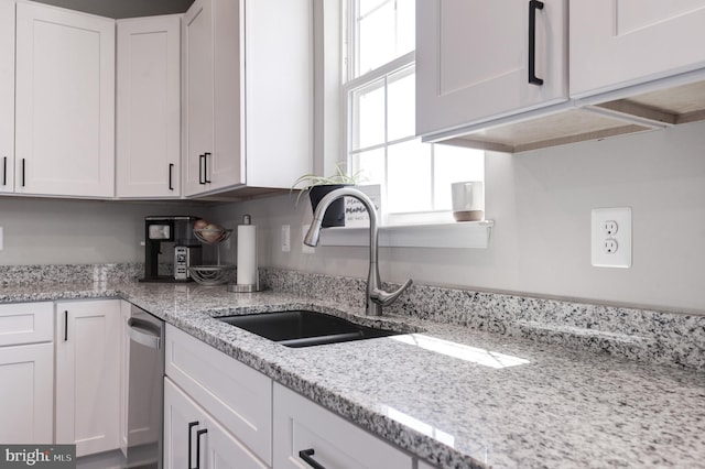 kitchen with light stone counters, sink, and white cabinets