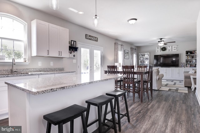 kitchen with a healthy amount of sunlight, sink, white cabinets, and hanging light fixtures