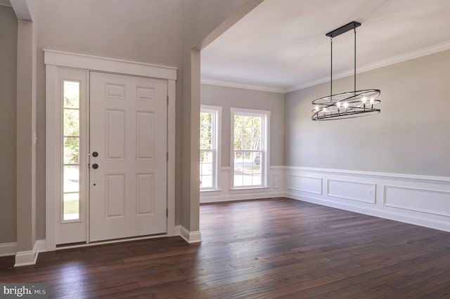 foyer with dark hardwood / wood-style flooring, ornamental molding, and a notable chandelier