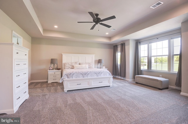 carpeted bedroom featuring ceiling fan and a tray ceiling