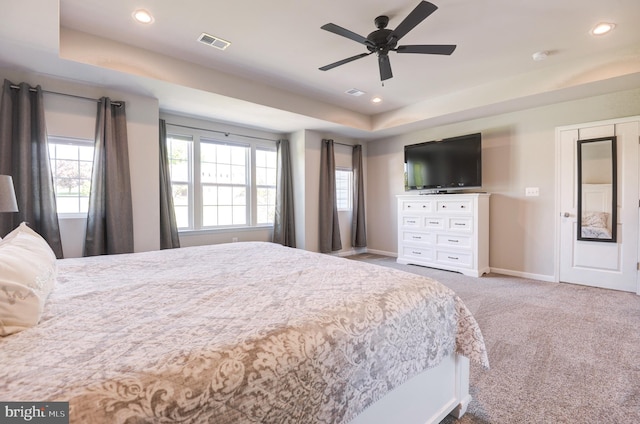 bedroom with ceiling fan, a raised ceiling, and light carpet