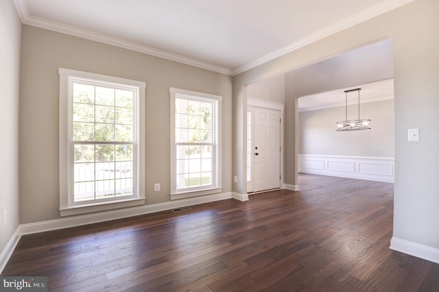 empty room with a chandelier, dark hardwood / wood-style flooring, and crown molding