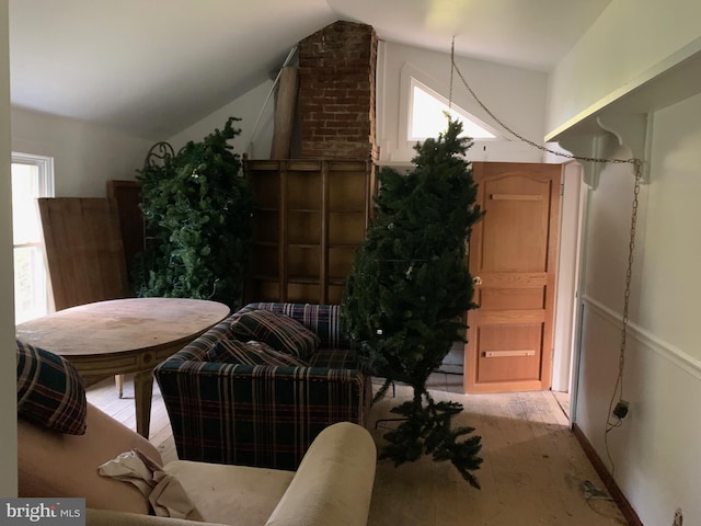 interior space featuring brick wall, light hardwood / wood-style floors, and vaulted ceiling