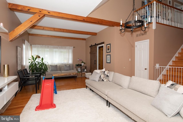 living room with a barn door, hardwood / wood-style floors, and an inviting chandelier