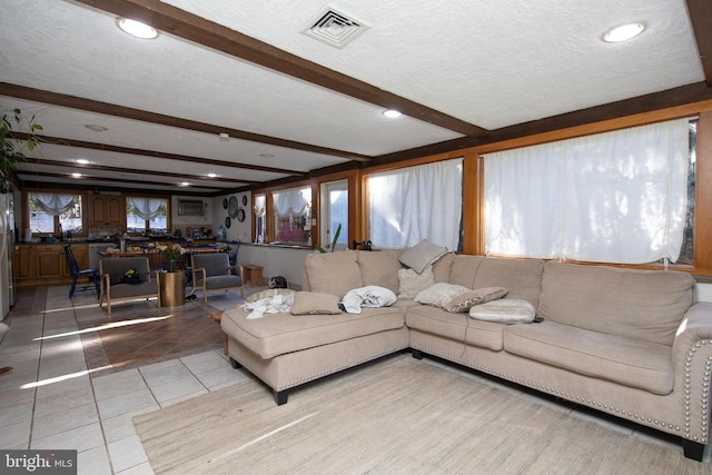 living room featuring light tile floors, a textured ceiling, and beam ceiling