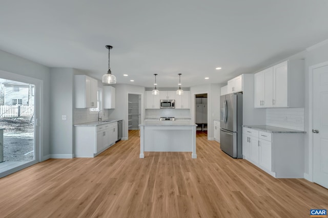 kitchen featuring pendant lighting, white cabinetry, appliances with stainless steel finishes, and light wood-type flooring