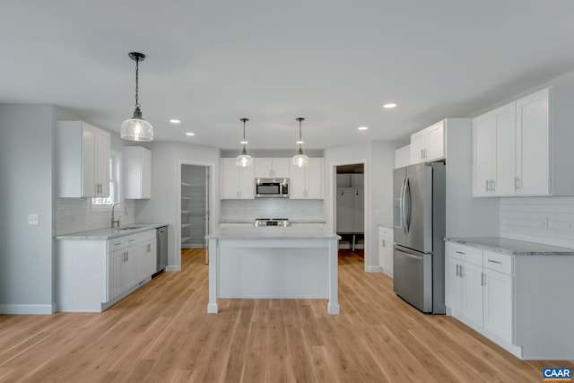 kitchen featuring appliances with stainless steel finishes, hanging light fixtures, white cabinetry, and light hardwood / wood-style floors