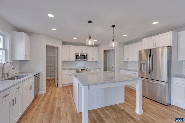 kitchen featuring decorative light fixtures, backsplash, light hardwood / wood-style floors, stainless steel appliances, and light stone counters