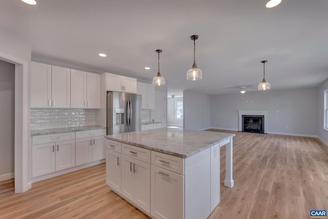 kitchen with white cabinets, stainless steel fridge with ice dispenser, light wood-type flooring, and pendant lighting