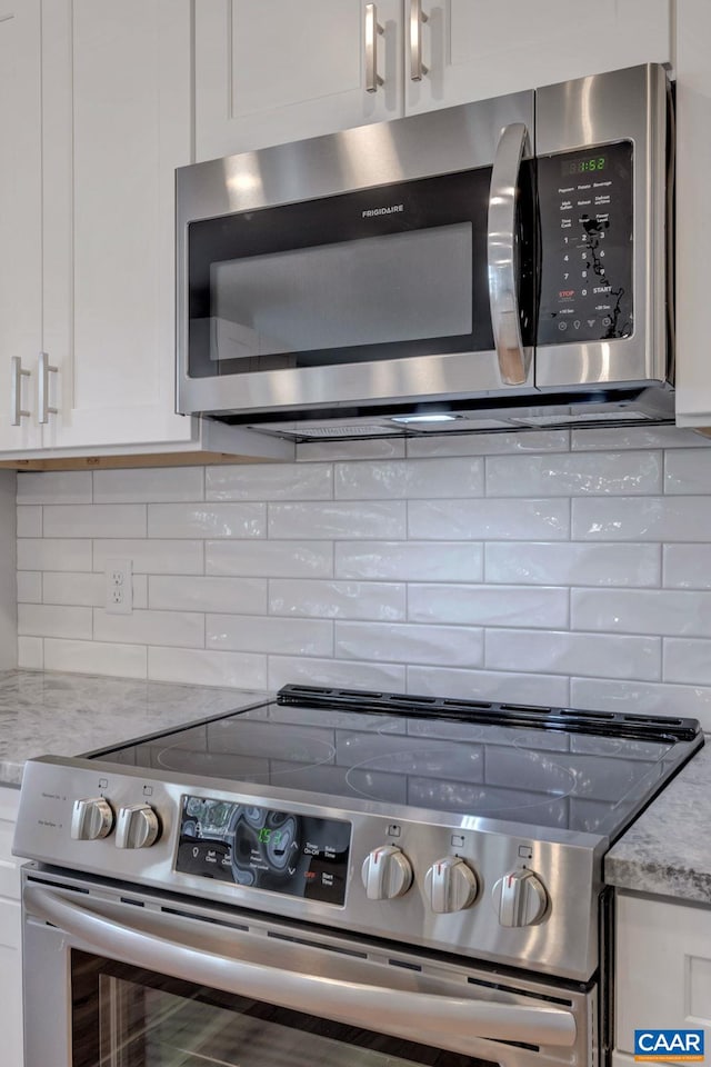 kitchen featuring tasteful backsplash, stainless steel appliances, white cabinetry, and light stone counters