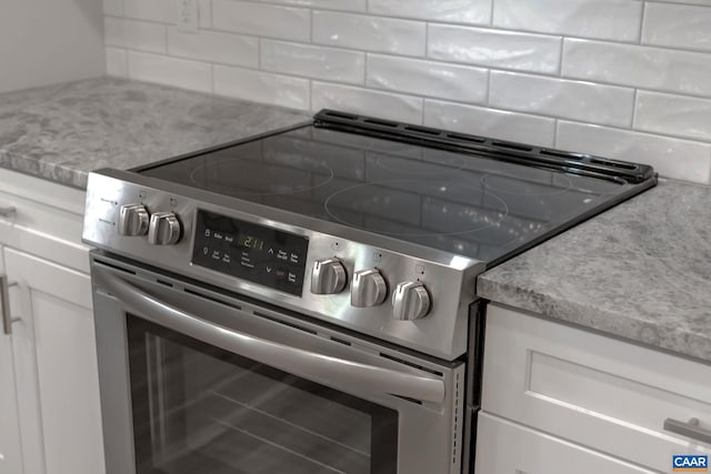 kitchen featuring backsplash, light stone counters, white cabinets, and stainless steel range with electric stovetop