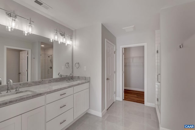 bathroom featuring a shower with shower door, dual sinks, large vanity, and hardwood / wood-style flooring